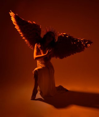 portrait of beautiful red head woman wearing long flowing fantasy toga gown with angelic  golden halo crown on studio background