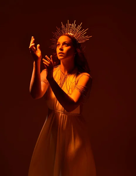 portrait of beautiful red head woman wearing long flowing fantasy toga gown with angelic  golden halo crown on studio background