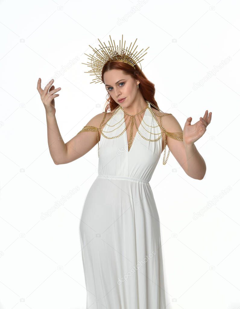 portrait of beautiful red head woman wearing long flowing fantasy toga gown with angelic  golden halo crown on studio background