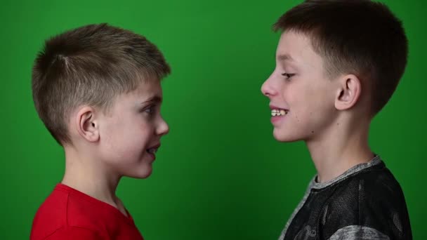 Δύο αγόρια φορούν οδοντιατρικές πλάκες, παιδιά σε ένα πράσινο φόντο σταθεί στο προφίλ. — Αρχείο Βίντεο