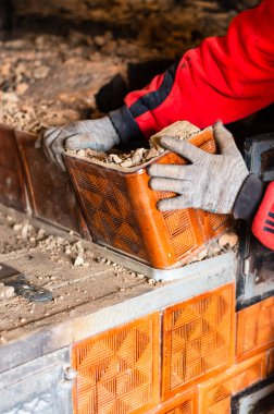 Eski bir tuğla soba, kurum içinde tuğla, eski mutfağı elleriyle söküyor, usta elleriyle tuğladan yuvarlanıyor. yeni
