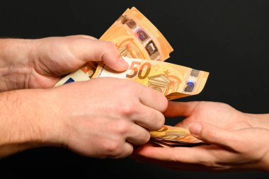 Siyah arka plandaki bir adamın elinde avroya para transferi ve iş ödülü olarak para almak. yeni