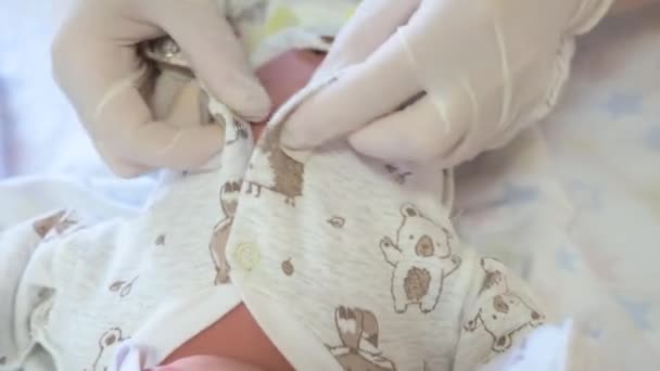 Eine Krankenschwester in einer Geburtsklinik kleidet ein Neugeborenes ein. — Stockvideo