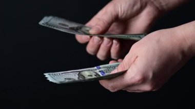 Yüz dolarlık banknotlar sayıyor, iş adamları para sayıyor, para siyah bir arkaplanda..