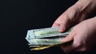 Yüz dolarlık banknotlar sayıyor, iş adamları para sayıyor, para siyah bir arkaplanda..