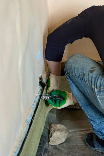 Installing damping tape with a stapler, close up of repair work in the house, damping tape for floor screed.