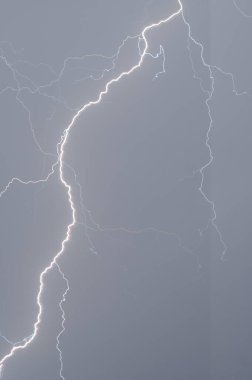 Fırtınadan önce parlak bir şimşek, gökyüzü yağmur bulutları ve yıldırımlarla kaplı, bulutlu bir gökyüzü.