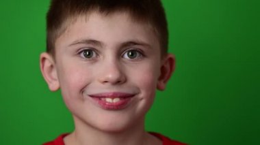 Çocuk elinde bebeğini iki dişle tutuyor, bebek yeşil arka planda..