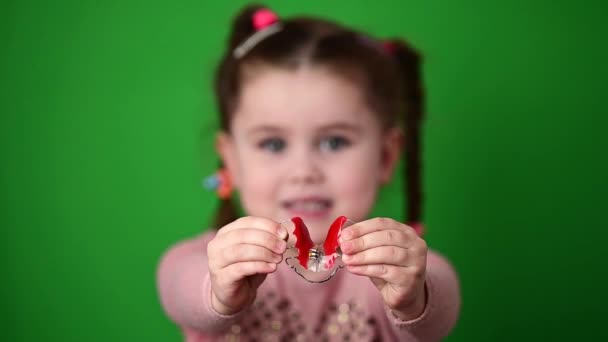 Das Kind untersucht und demonstriert eine Zahnplatte zur Straffung schiefer Zähne. — Stockvideo