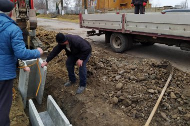 Dolyna, Ukrayna 22 Kasım 2021: Kazı ekibi kırsal bölgelerde yağmur suyu boşaltmak için beton tepsiler, su akıtmak için somut ürünler, t biçimli kavşaklar ve beton drenaj kanalları kuruyor.