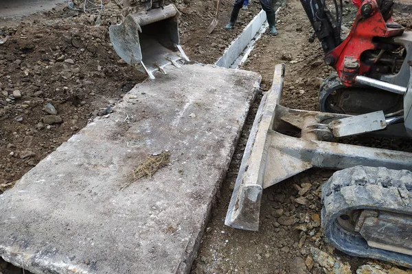 La pelle met des dalles de béton pour se déplacer dans la gouttière, travaux de construction avec une pelle. — Photo