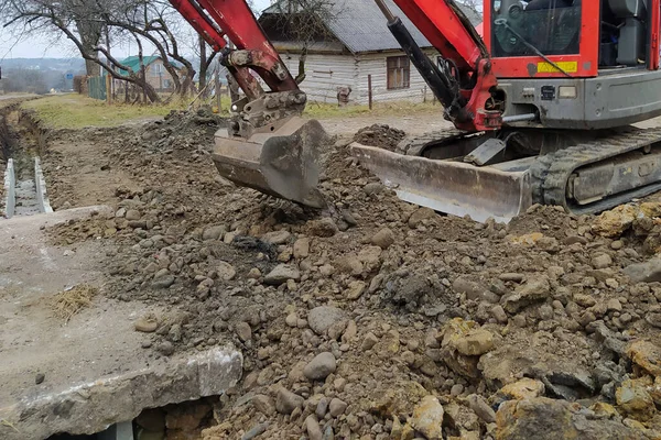 Excavator menempatkan lempengan beton untuk bergerak melalui selokan, pekerjaan konstruksi dengan ekskavator. — Stok Foto