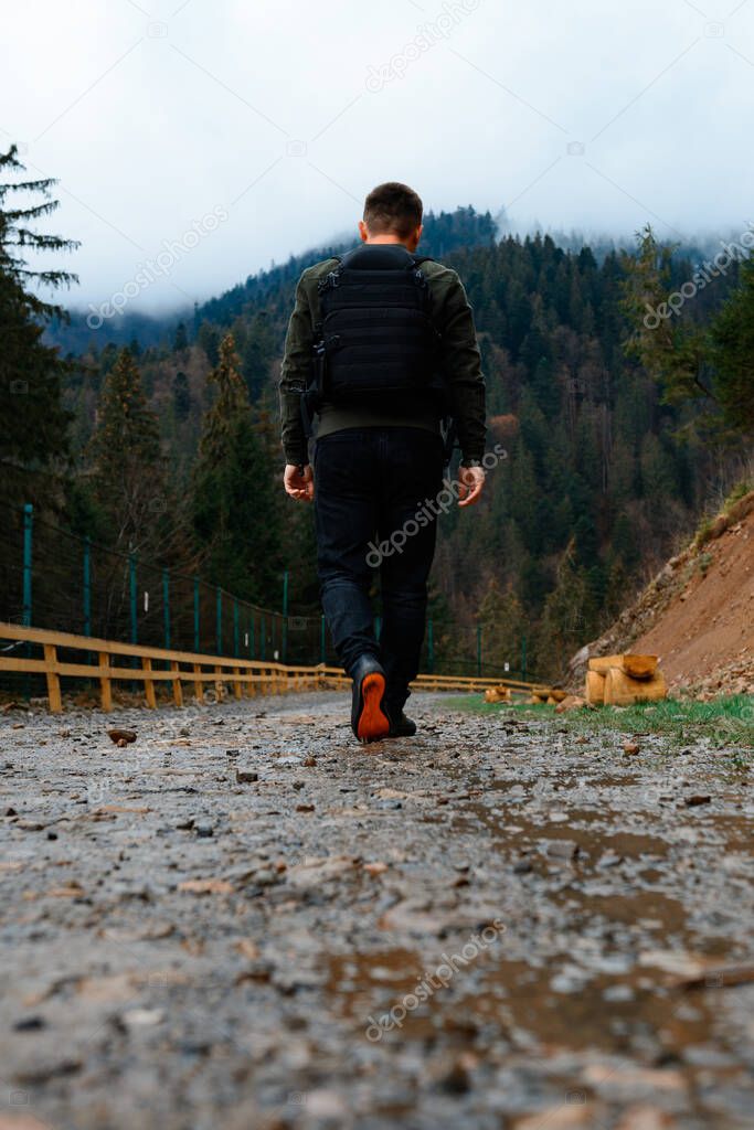 Walking on forest roads, a man walking alone on a forest road against the backdrop of a mountain top with fog, the road is fenced.