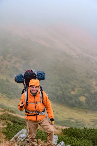 男は霧の中で山に登ると 男は彼の背中にバックパックを運ぶ 一晩の滞在で観光旅行 — ストック写真