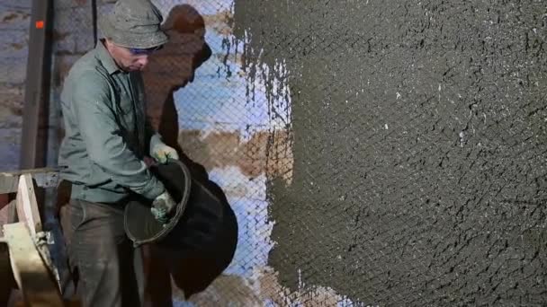 El proceso de enlucido de la pared, un hombre con una paleta en las manos enluta la pared con un mortero líquido de hormigón. — Vídeos de Stock