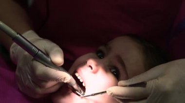 Bir çocukta bebek dişi tedavisi, bir doktor bakımı için dişlerini döker..
