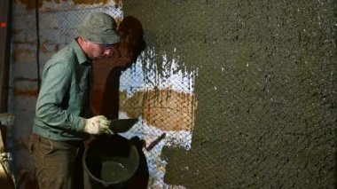 Duvarı alçılama işlemi elinde malayla duvarı beton bir havan topuyla kaplıyor..