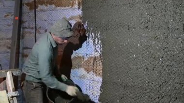 Duvarı alçılama işlemi elinde malayla duvarı beton bir havan topuyla kaplıyor..