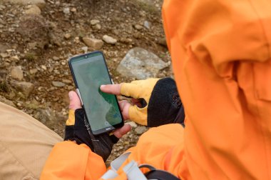 Adam dağlarda akıllı telefon kullanarak yolu kapatıyor, dağlarda navigatör, dağlarda navigatör olarak akıllı telefon kullanıyor..