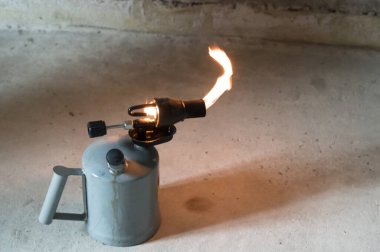 Alevli gaz lambası, inşaatta pürmüzün kullanılması, eldivenli bir adamın eli..
