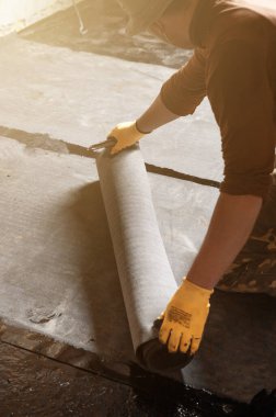 İşçi su yalıtımı rulosunu çözüyor ve su geçirmez hale getirip reçineye takıyor..