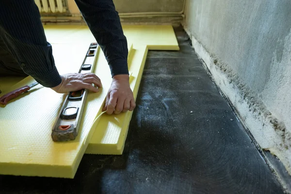 マスターのクローズアップは 床に展開されたポリスチレンのサイズをカット 家の床断熱材のプロセス 修理作業だけで — ストック写真