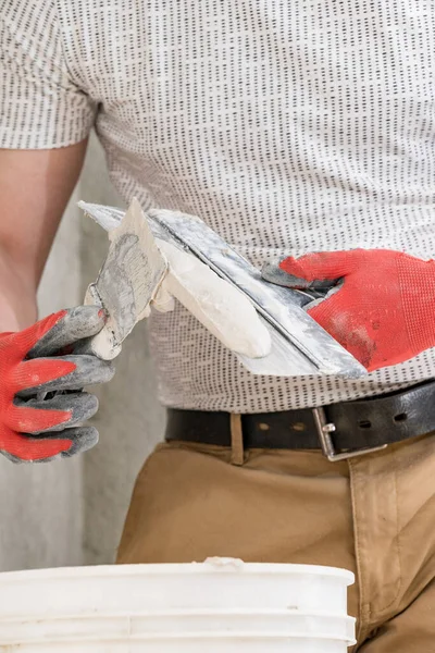 Lime plaster on a spatula, repair and decoration work with lime plaster, two dirty spatulas, lime plaster in a bucket.