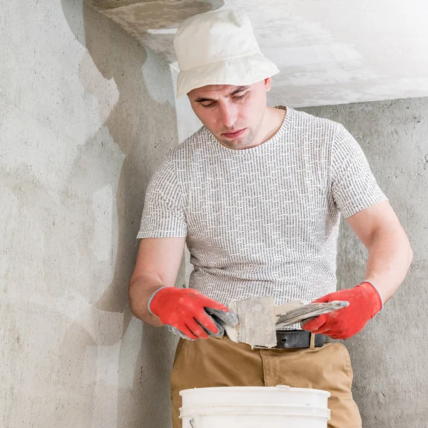 The master works with lime plaster, leveling the wall with a spatula and lime plaster, repairing work on leveling the walls.