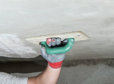 Kireç alçısını nemlendirici süngerle düzleştirirken, usta tavanı inşaat rendesiyle ovuyor..