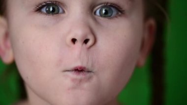 At kuyruklu güzel görünümlü bir kız kameraya bir öpücük gösteriyor, yeşil arka planda bir çocuk. yeni