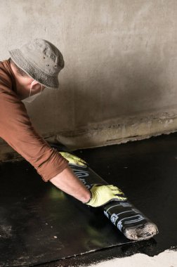 İşçi su yalıtımı rulosunu çözüyor ve su geçirmez hale getirip reçineye takıyor..