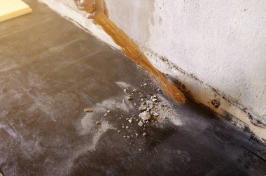 Bir işçi süpürge, barut ve küçük beton parçacıklarıyla inşaat enkazı süpürür..