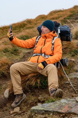 Dağlarda telefonla konuşan bir adam, dağlarda mobil ağ ve bağlantı, dağlarda mobil iletişim, dağlarda video görüşmeleri.