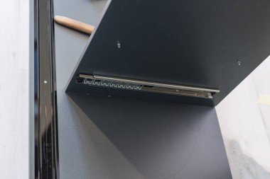 Bir durumda sürgülü mekanizmanın vidalanması, bir çekmece için sürgülü mekanizma, gri renkli bir kayan gardırop.