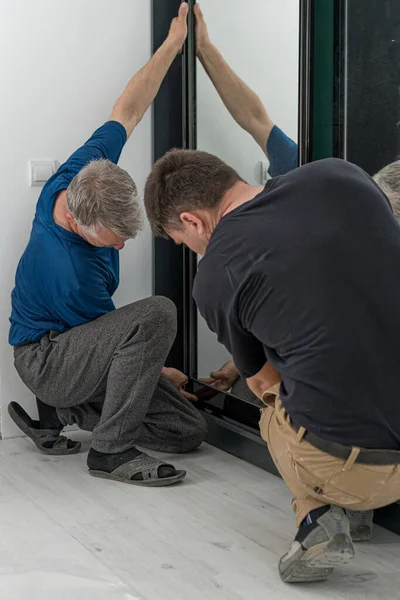 Assembly of a sliding wardrobe, a door of a wardrobe with a mirror, the master and the assistant make a sliding wardrobe.