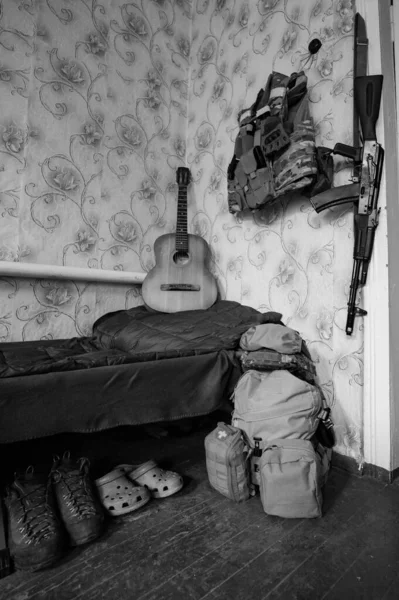 A soldier\'s machine gun and military ammunition next to a guitar, the war in Ukraine, folded military shoes.