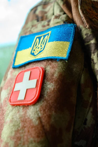 Military medic sign. Chevrons on the Ukrainian military pixel uniform, blue-yellow flag and red cross sign.