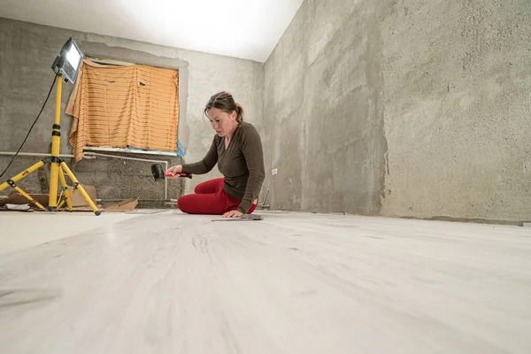 Woman installs quartz vinyl flooring at home, exhausted woman from work, installation of quartz vinyl flooring.