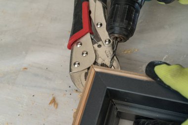 Zanaatkar köşedeki bağlantı için kapıyı deliyor, pense iki kapı levyesini tutuyor, kapı takılı..