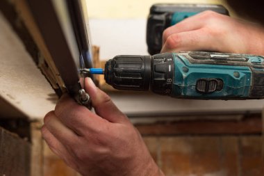 Drilling and installation of interior doors, the craftsman makes a hole in the door frame with a hand drill, doors and installation.