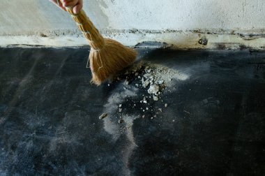 Bir işçi süpürge, barut ve küçük beton parçacıklarıyla inşaat enkazı süpürür..