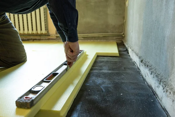 マスターのクローズアップは 床に展開されたポリスチレンのサイズをカット 家の床断熱材のプロセス 修理作業だけで — ストック写真
