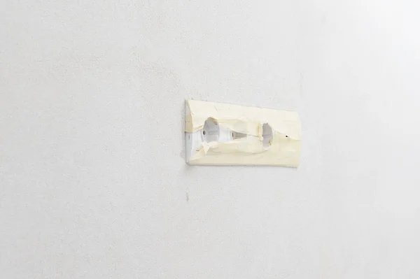 White sockets on a white wall, a socket for a TV antenna, sockets with masking tape.