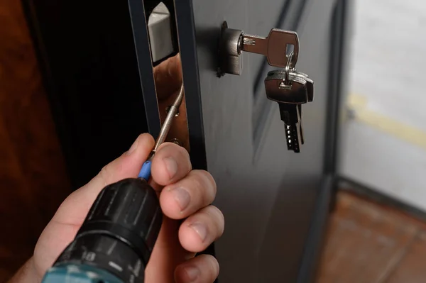 Installation of a lock and door handle to an interior door, a locksmith works with the door, the keys are in the door lock.