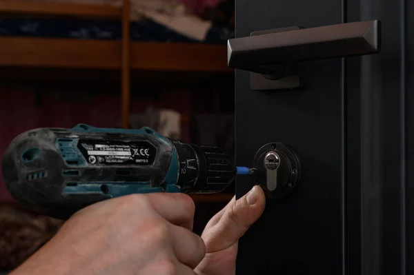 Installation of a door lock, a carpenter installs a door lock in a door, close-up work, fixing the core of the lock.