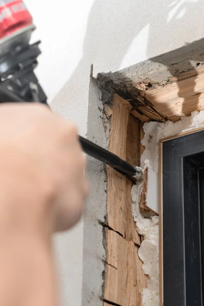 a man uses a spray gun with his hand and fills the gap with construction foam between a new wooden door and a wall, the process of installing a door.