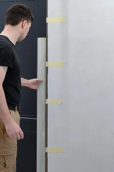 Checking the door frame for evenness of the surface after installation with a metal rule, installing the door in the room.