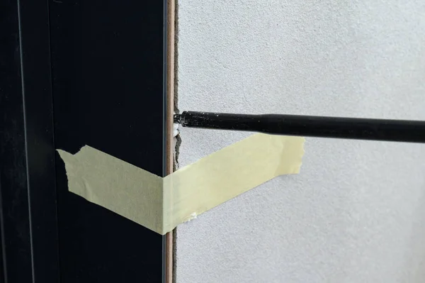The use of painter\'s tape in the installation of the door, the tape restrains the deformation of the door during the filling of the gaps between the door and the wall with foam, repairs.