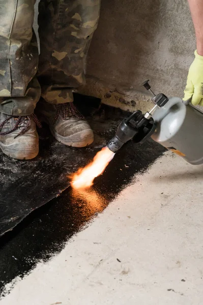 installation of waterproofing coating on the floor with a blowtorch and resin, repair work at home.