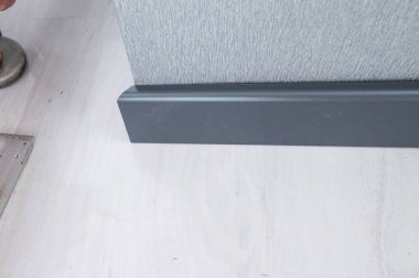 The plinth is dark gray to match the color of the door, mounting the plinth in the room, light gray floor and dark plinth.